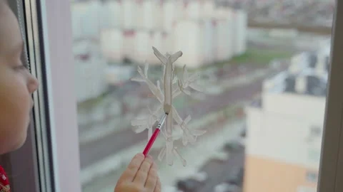 Child draw snowflake on window with paint. Real time Stock Footage 166161346