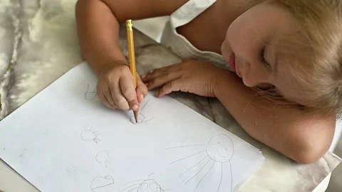 Child drawing basic shapes with pencil on white sheet of paper. Stock Footage 335389420