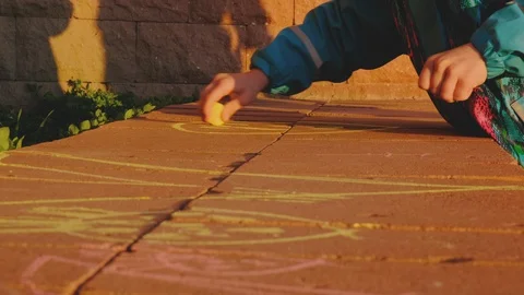 Child Drawing with Chalk on Bricks During Sunset Golden Hour Stock Footage 126913986