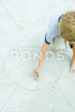 Child drawing circle in the sand with a stick, cropped view Stock Photos