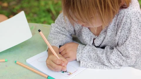 Child drawing with fineliners in notebook in a summer garden Stock Footage 304328555