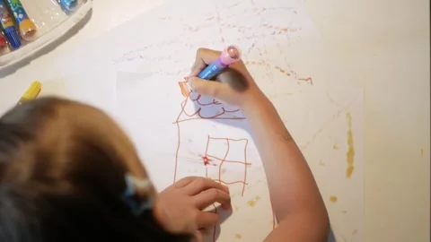 Child drawing a house behind the table Video stock 263068917