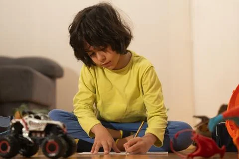 Child drawing on paper while sitting on floor at home Stock Photos