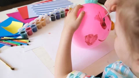 Child drawing pattern of paints fun smile on the balloon. Fun toy. Video stock 166476721