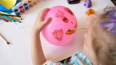 Child drawing pattern of paints smile on the balloon Video stock 153885374