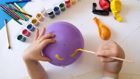 Child drawing pattern of paints smile on the balloon. Video stock 155082279