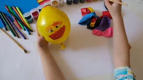 Child drawing pattern of paints smile on the balloon. Video stock 286836797