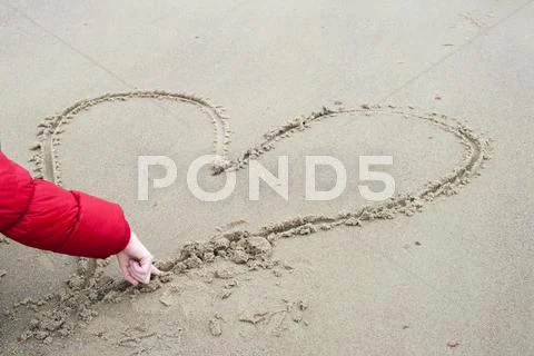 Child is drawing in the sand a heart Stock Photos