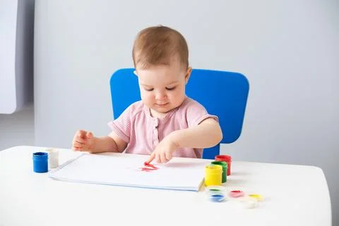 Child is drawing on white sheets with finger paints Stock Photos