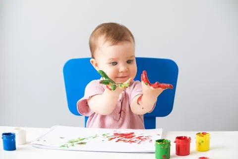 Child is drawing on white sheets with finger paints Stock Photos