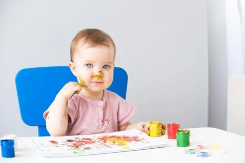Child is drawing on white sheets with finger paints Stock Photos
