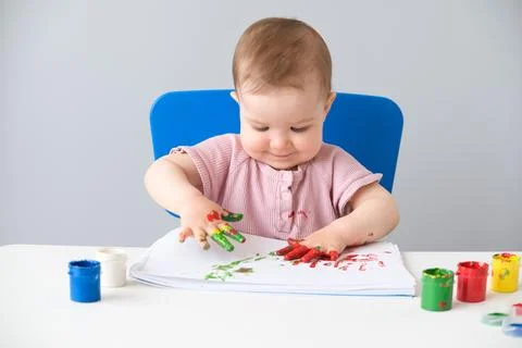 Child is drawing on white sheets with finger paints Stock Photos