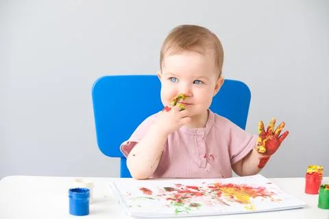 Child is drawing on white sheets with finger paints Stock Photos