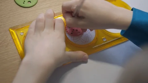 A child draws with ballpoint pen patterns using the graphical ruler Stock Footage 129402812