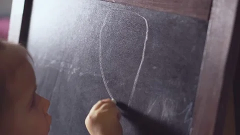 Child draws on the blackboard with chalk, close up. Video stock 166455765