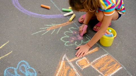 The child draws with chalk on the asphalt. Selective focus. Stock Footage 157311596