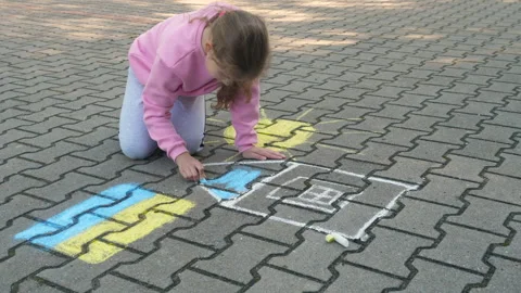 Child Draws With Chalk on Pavement Drawing of House, Sun and Ukrainian Flag.. Stock Footage 331268134
