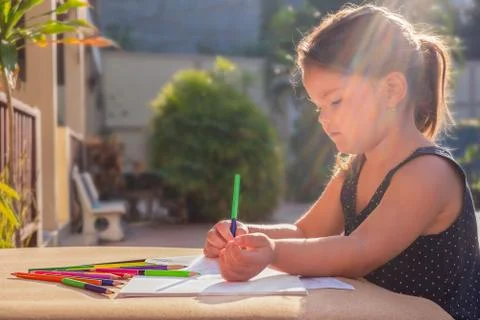 The child draws with multi-colored pencils in the yard Stock Photos