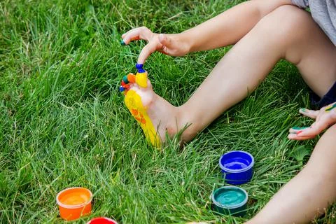 The child draws a pattern on the leg. A funny drawing with bright colors on t Foto stock