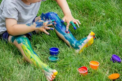 The child draws a pattern on the leg. A funny drawing with bright colors on t Stock Photos