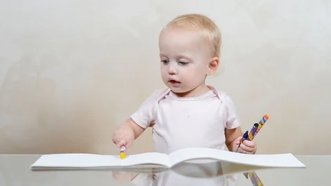 The child draws scribbles in the album, then takes crayons and joyfully leaves Video stock 117814355