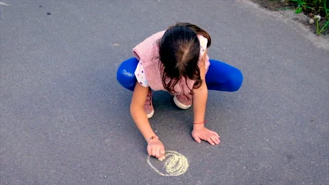 The child draws the sun on the pavement. Selective focus. Video stock 154988230