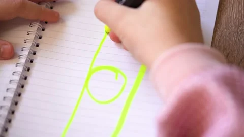 Child draws tree in notebook with green marker 库存影片 223369115