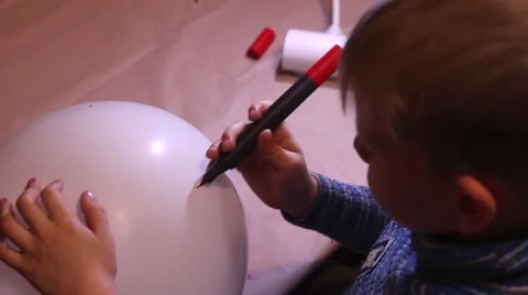 The Child Draws Using a Red Marker on a White Balloon. Stock Footage 68826935
