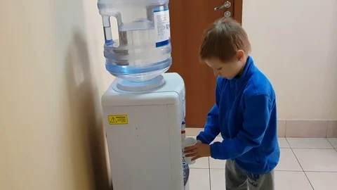 The child draws water from the cooler and drinks water Stock Footage