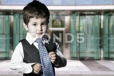 Child dressed businessman smiling in front of building Stock Photos