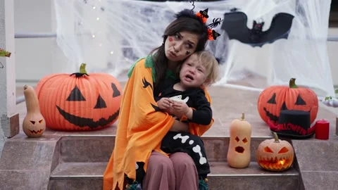 A child dressed as a skeleton for Halloween is crying from fright and a mother Vidéo 219756138