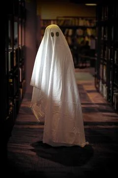 Child dressed as a white ghost in a library room 写真素材