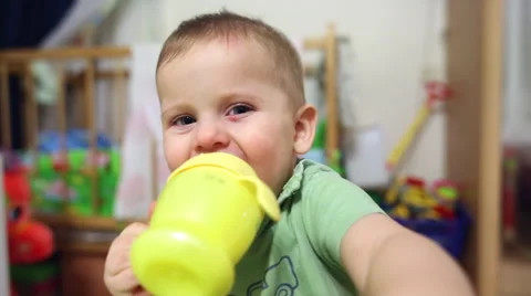 The child is drinking from a drinking bowl and a hand covering the lens Stock Footage 64235586