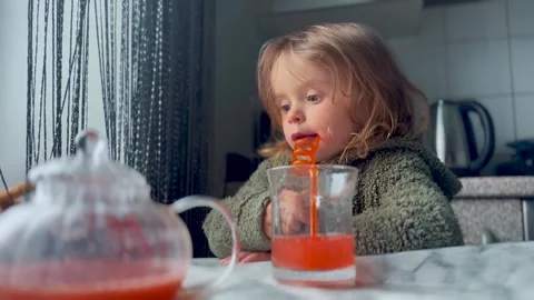 Child Drinking Juice with Straw at Table Indoor Scene Video stock 333149633