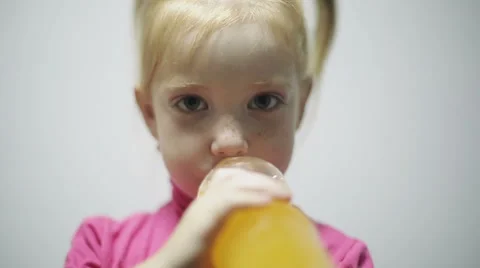 Child drinking orange beverage at gray background in a studio Stock Footage 53189842