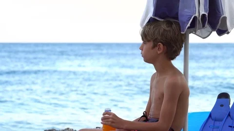 Child Drinking Orange Juice on the Beach Vidéo 79905491