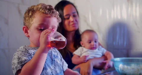 A child is drinking tea while waiting for the popcorn to be ready 스톡 동영상 170731681