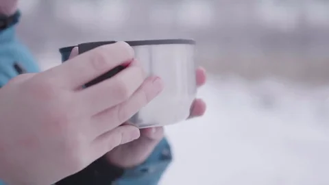 The child is drinking tea in winter outdoors in the park Видео 83512557