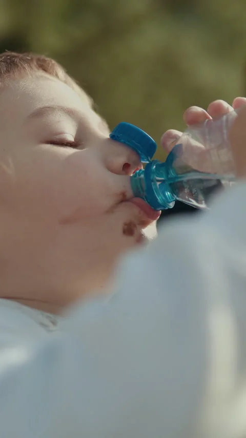 Child drinking water from plastic bottle in a park Stock Footage 327128463