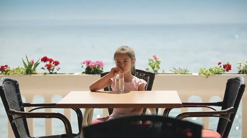 Child is drinking water in the restaurant which is located on the shore Stock Footage 39828131