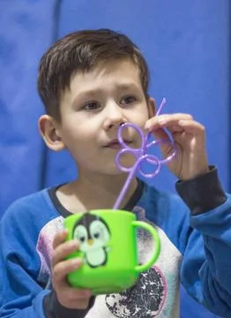 The child drinks a beverage through a straw from a cup, Stock Photos