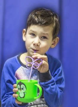 The child drinks a beverage through a straw from a cup, Stock Photos