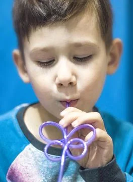 The child drinks a beverage through a straw from a cup, Stock Photos