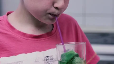 Child drinks fresh lemonade with mint leaves using straw. Boy quenches his thirs Stock Footage 198489593