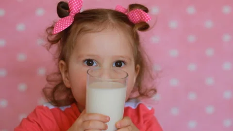 The child drinks a milk. A nice little girl holding a glass with drink in her Stock Footage 88965005