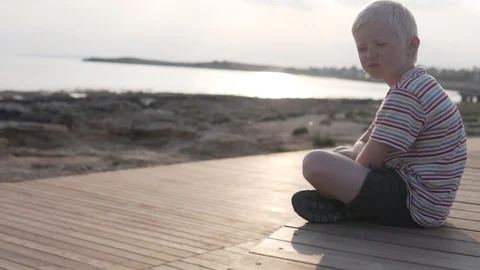 A child drinks water from a bottle on the background of a sunset in the sea Stock Footage 108313224