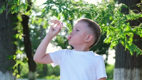 The child drinks water from a plastic bottle. Video stock 246500431