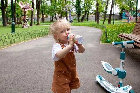 Child drinks water while playing in a park on a sunny day Generative AI Stock Photos