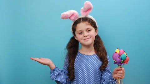 Child in Easter bunny ears holding colorful eggs with open palm for promotion Stock Footage 263421593