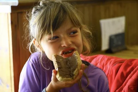 Child eating bread with chocolate spread indoors Fotos de archivo